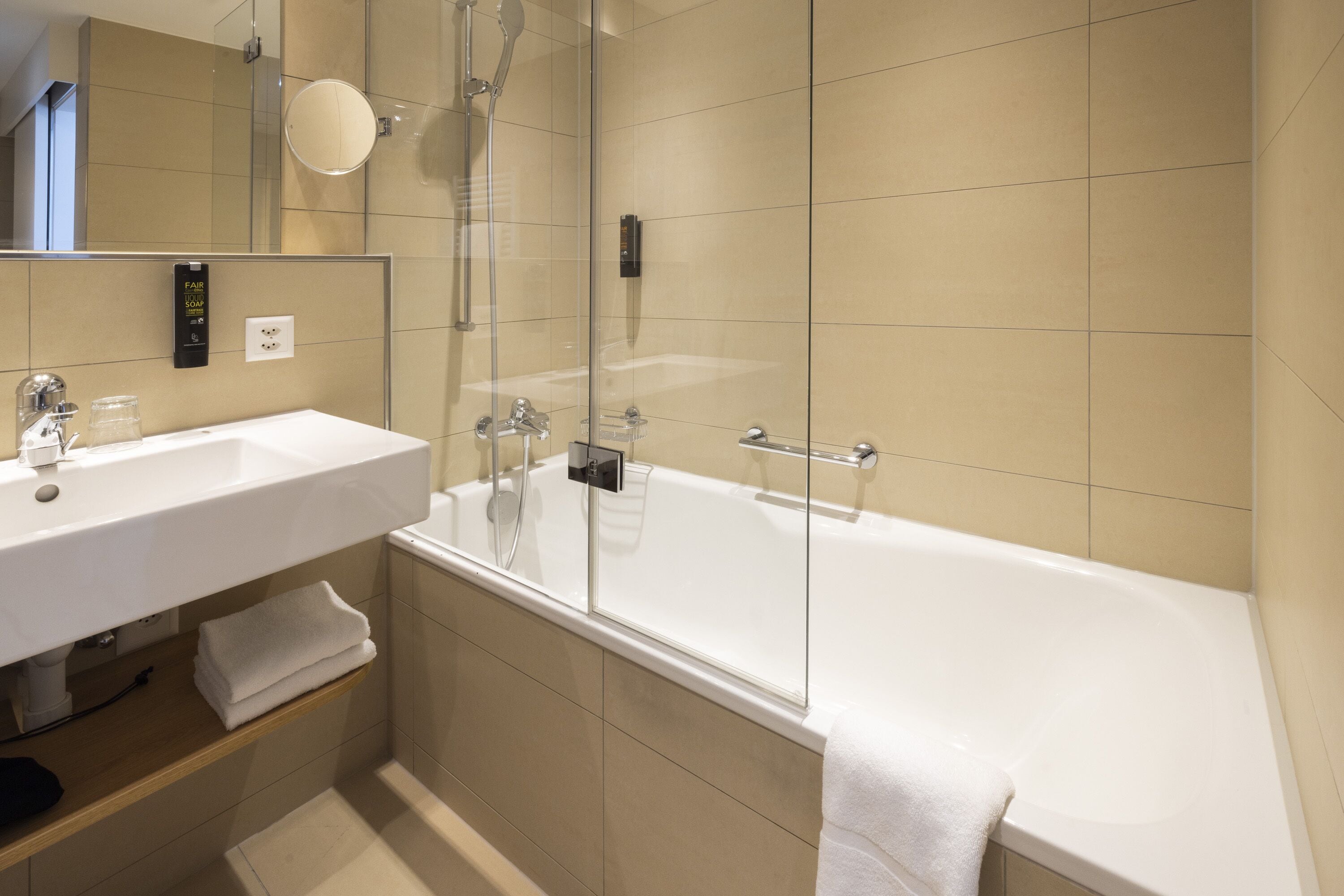 A modern bathroom with a white sink, mirror, and bathtub.