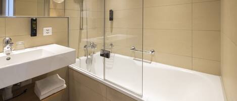 A modern bathroom with a white sink, mirror, and bathtub.