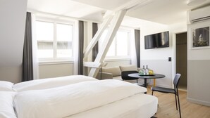 A hotel room with a bed, a desk, a chair, a TV, and a window with curtains. - Fred Hotel Hauptbahnhof (Zürich)