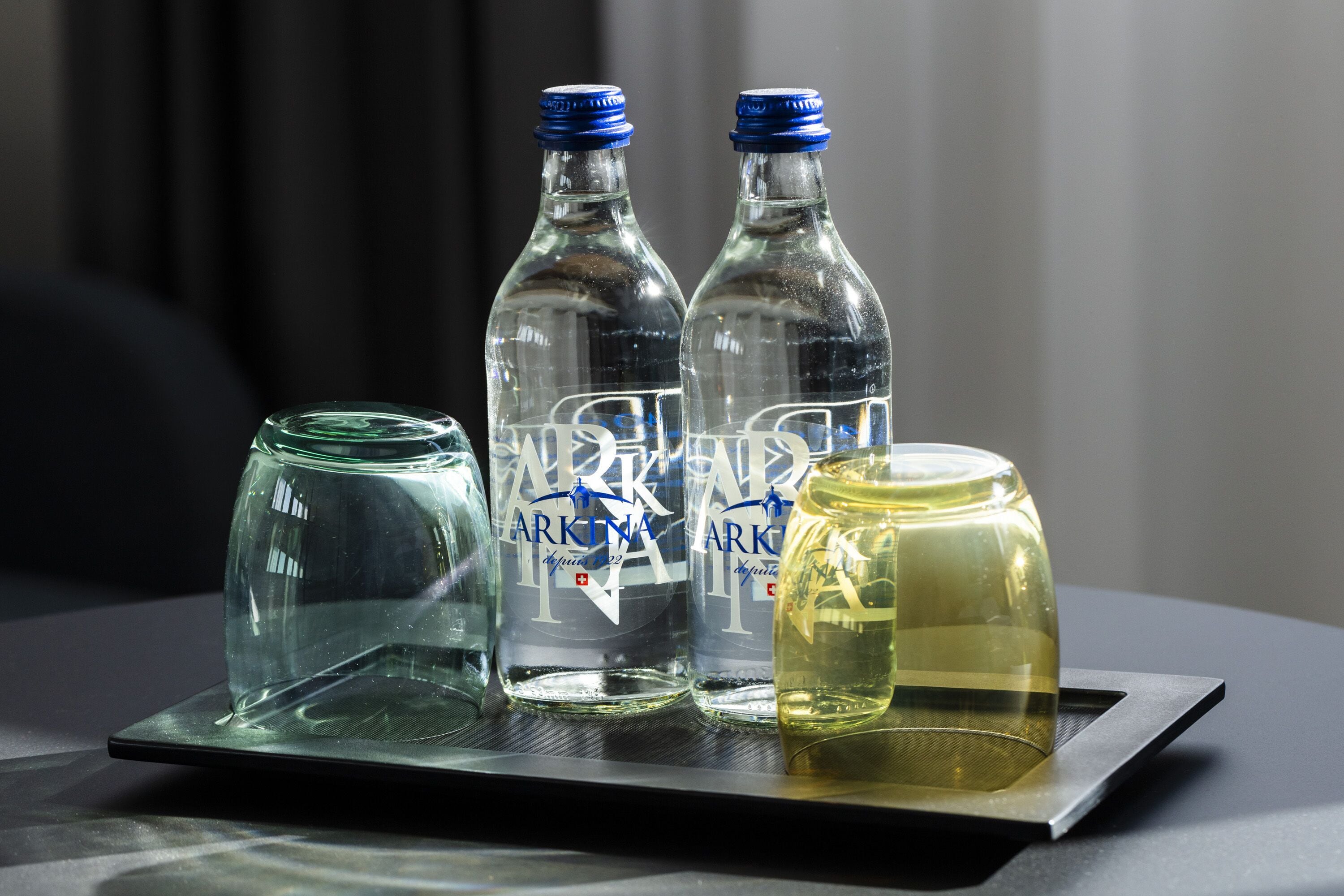 Three bottles and a glass jar on a tray.