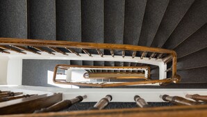A spiral staircase with wooden handrails and a white central column. - Fred Hotel Hauptbahnhof (Zürich)