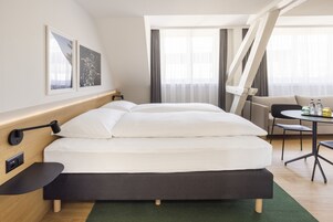 Moderni hotellihuone, jossa on suuri sänky, työpöytä, tuoli ja sohva.