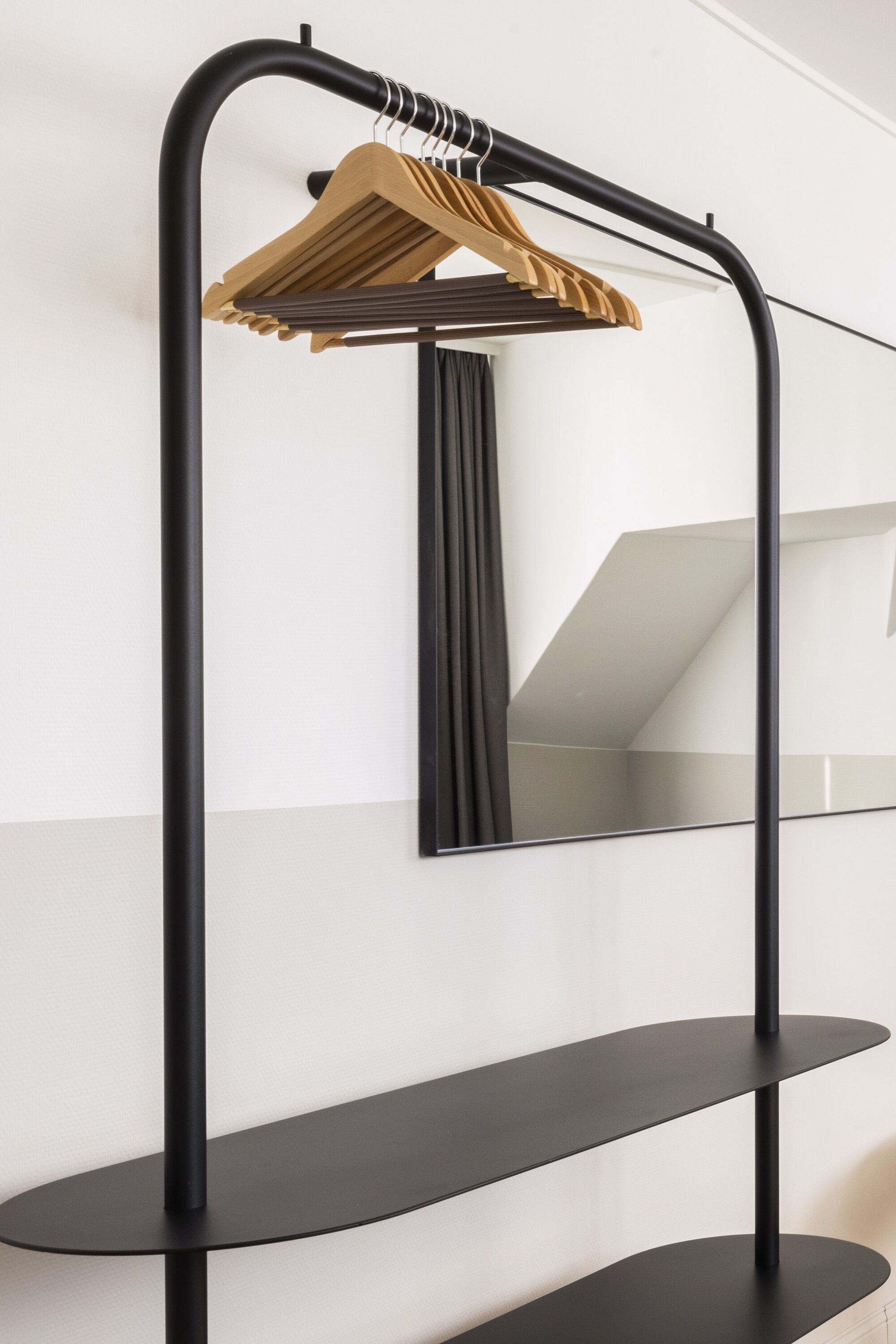 A black metal shelf unit with two levels and a wooden hanger.