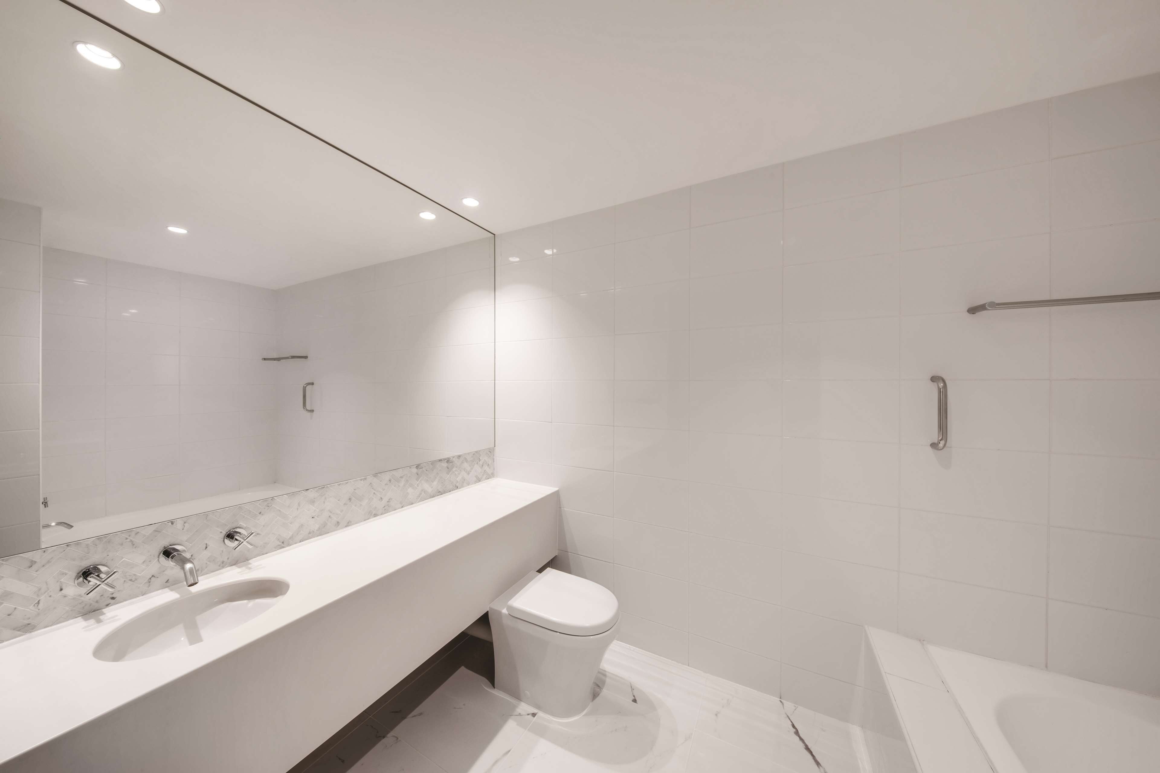 A modern bathroom with a white sink, toilet, and bathtub.