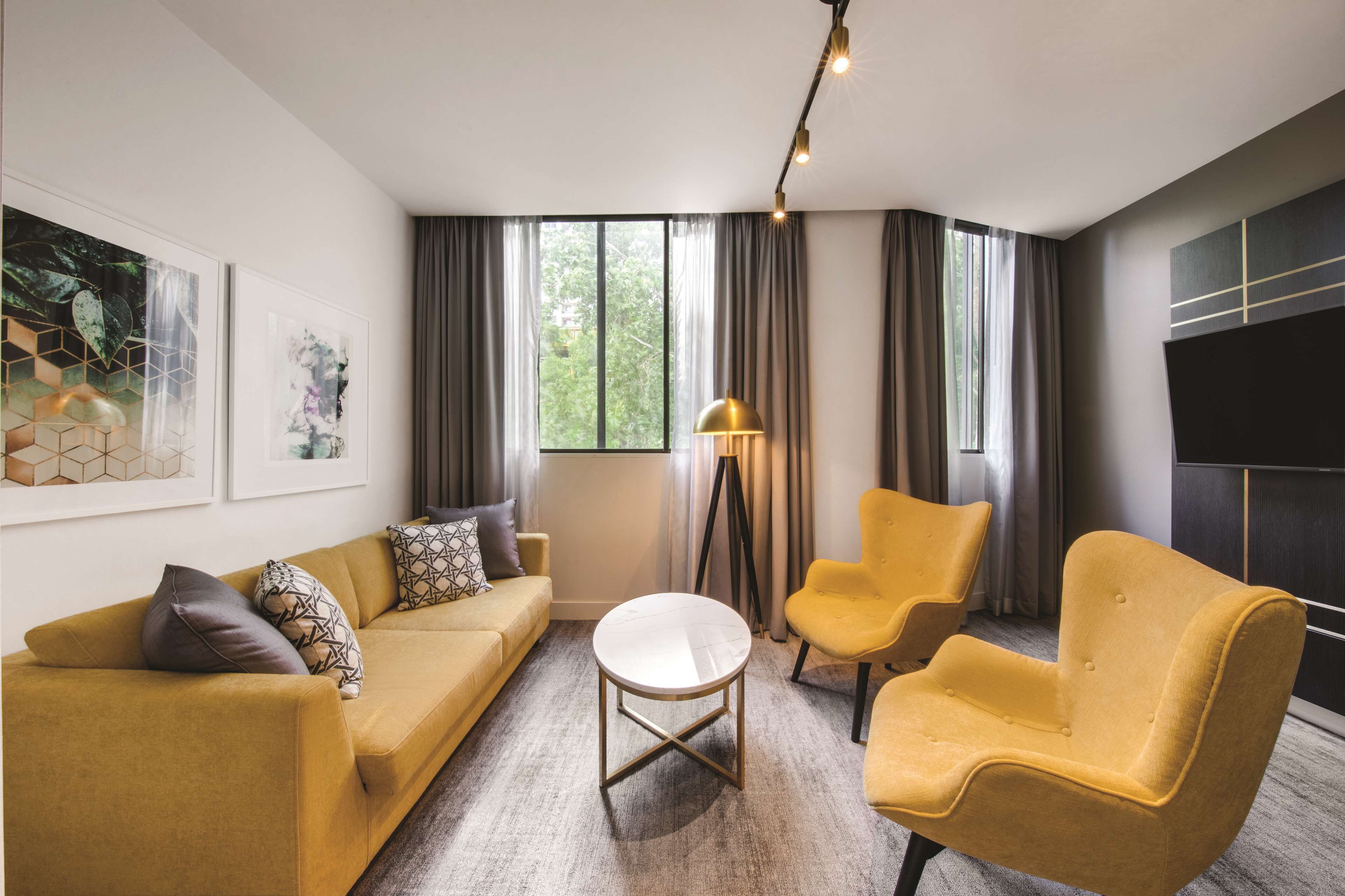 A modern living room with a sofa, two armchairs, a coffee table, and a floor lamp.