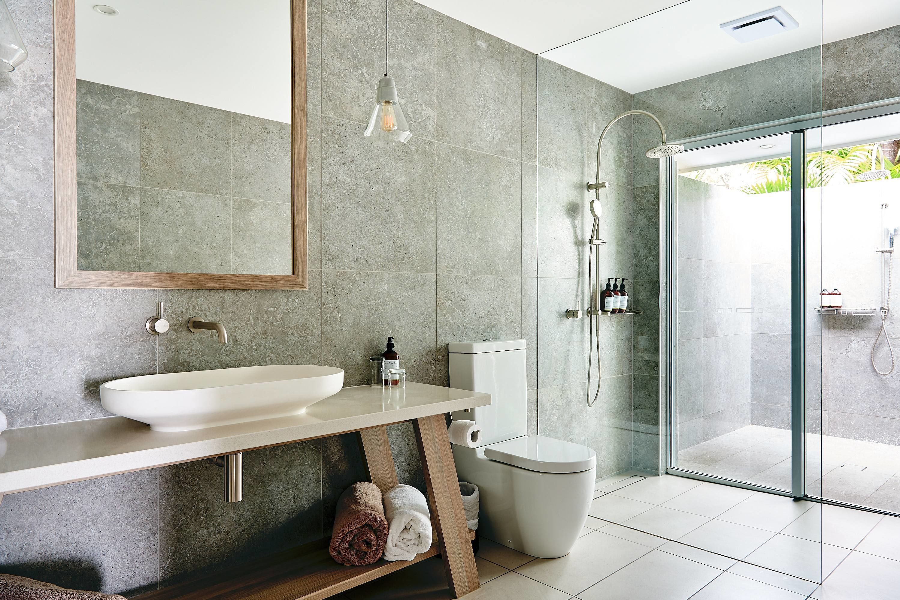 Ein modernes Badezimmer mit einem großzügigen Waschbecken, Toilette und einer Duschkabine aus Glas.