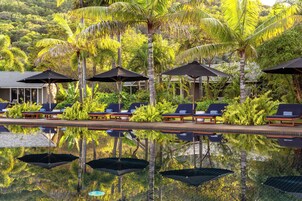 Una piscina al aire libre, sombrillas, sillones reclinables de piscina