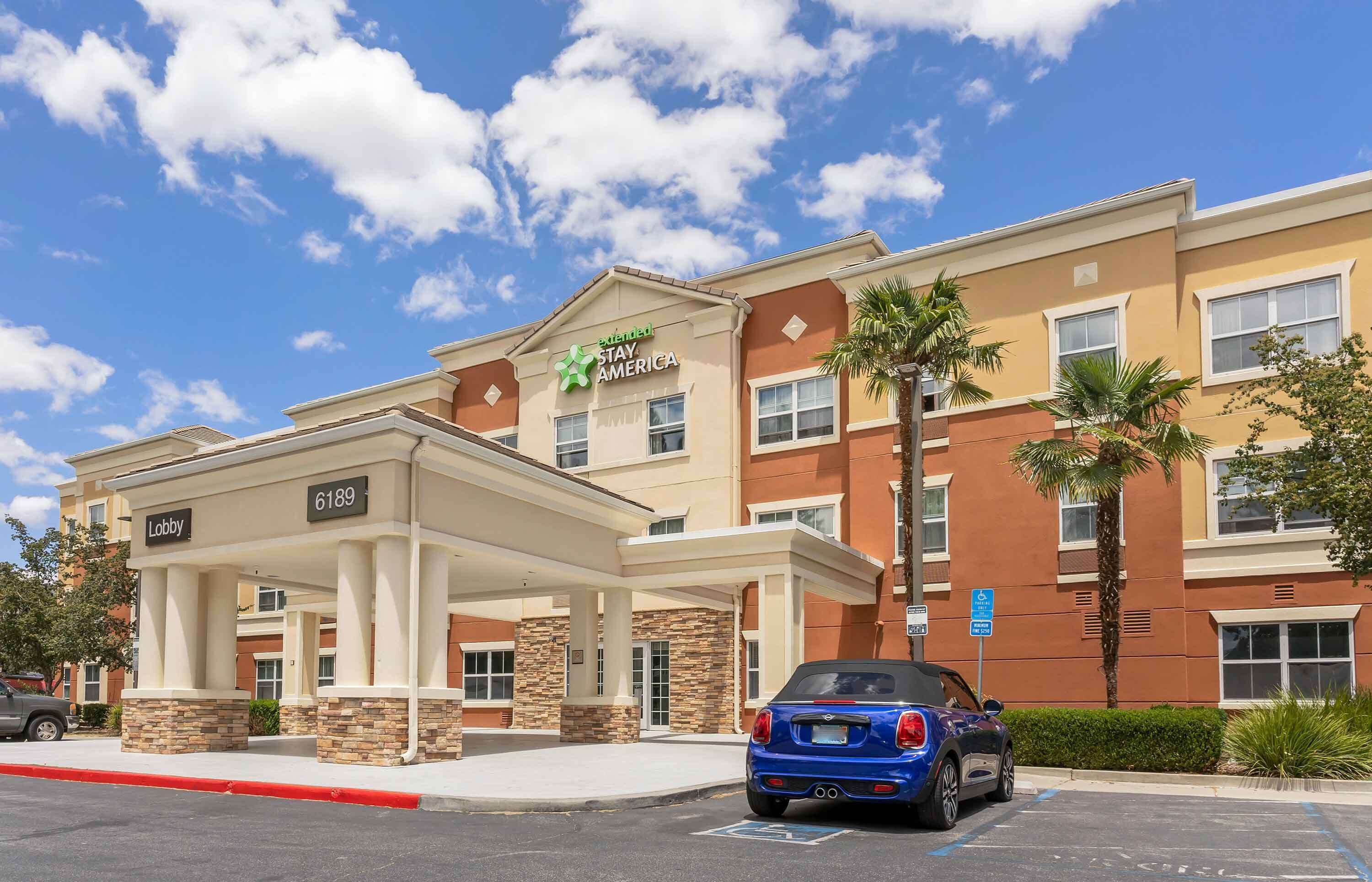 A hotel with a 'Stay America' sign, a 'Lobby' sign, and a parking area with a blue car.
