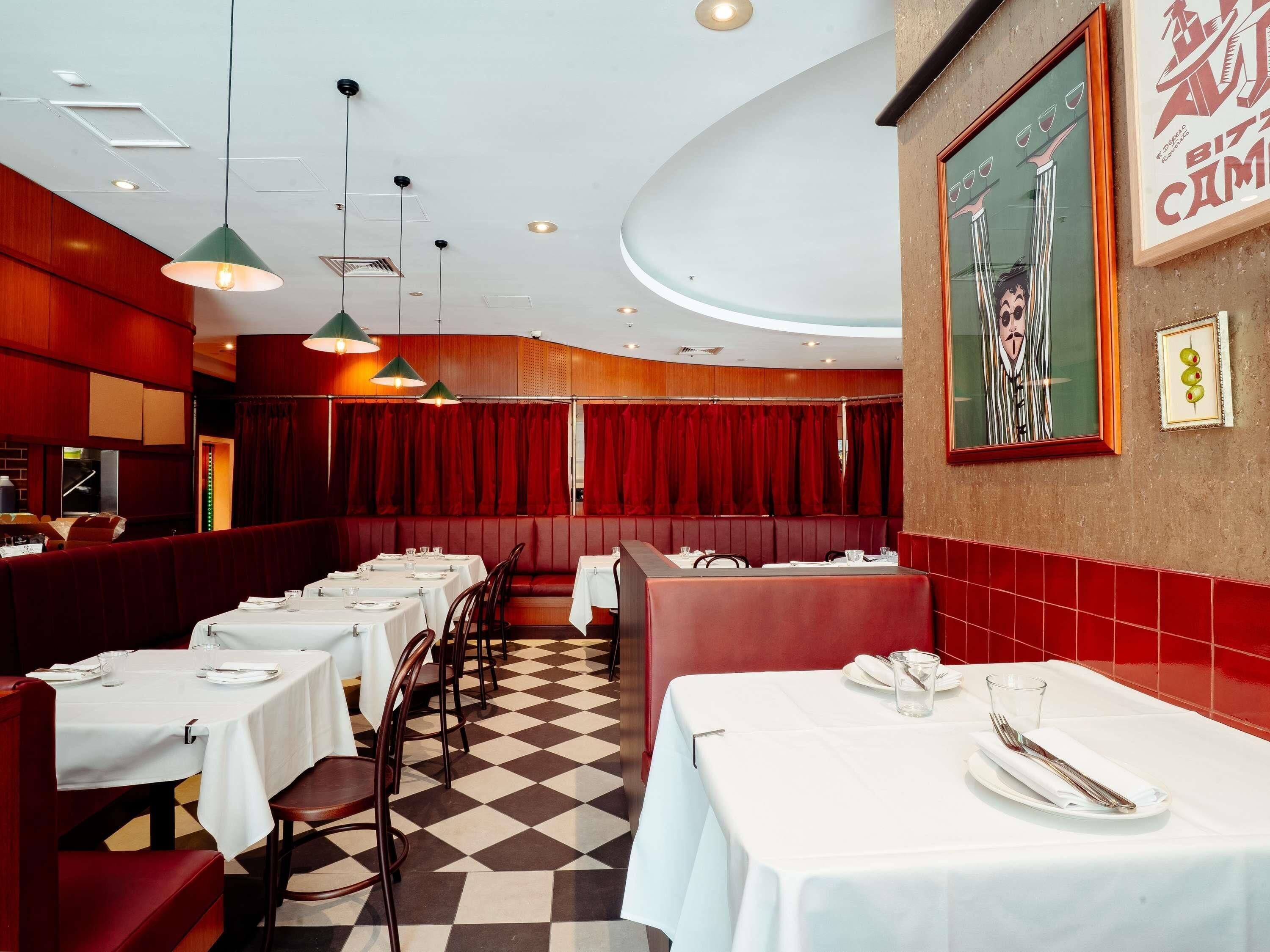 Ein Restaurant mit Sitzboxen, Tischen und einem Schachbrettmuster auf dem Boden.