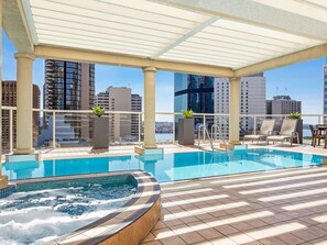 A rooftop pool area with a hot tub, lounge chairs, and a view of the city skyline. - Mantra 2 Bond Street Sydney (Sydney)