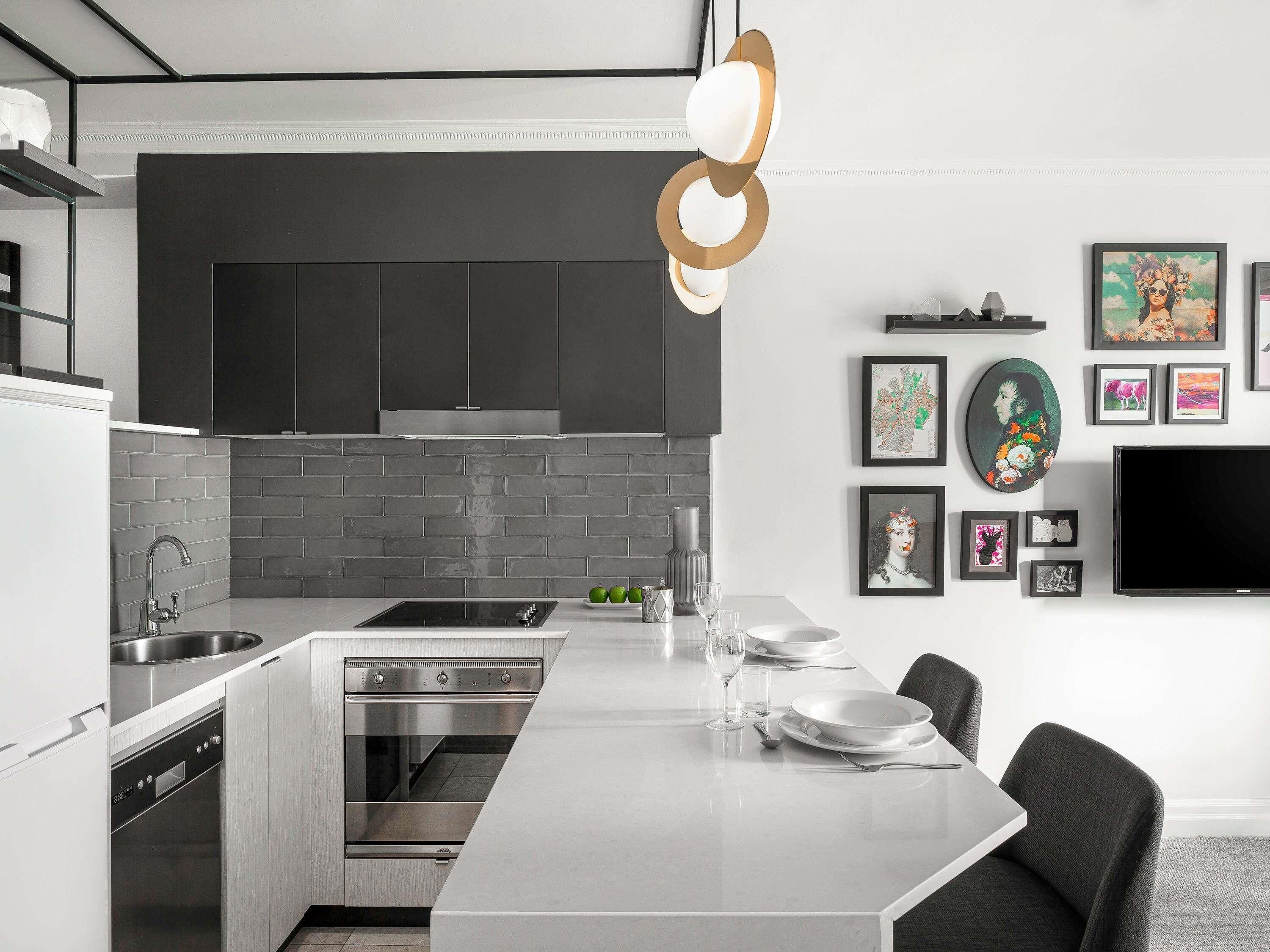 A modern kitchen with a central island, built-in oven, and a dining area with a flat-screen TV.