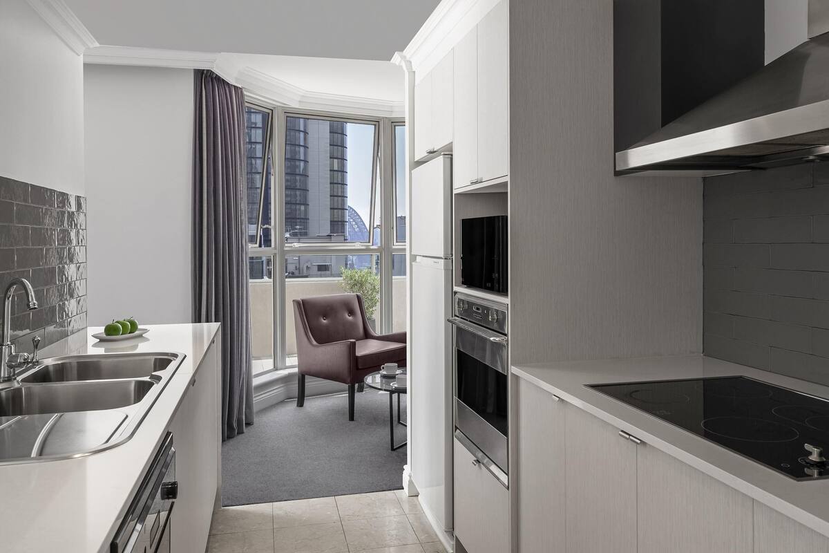 A modern kitchen with a built-in oven, a stovetop, and a large window with a view of the city.