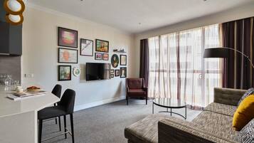 A modern living room with a sofa, armchair, dining table, and artwork on the walls.