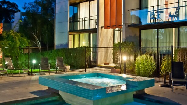 A modern hotel with a rooftop pool area, including lounge chairs and a hot tub. - Phillip Island Apartments (Cowes)