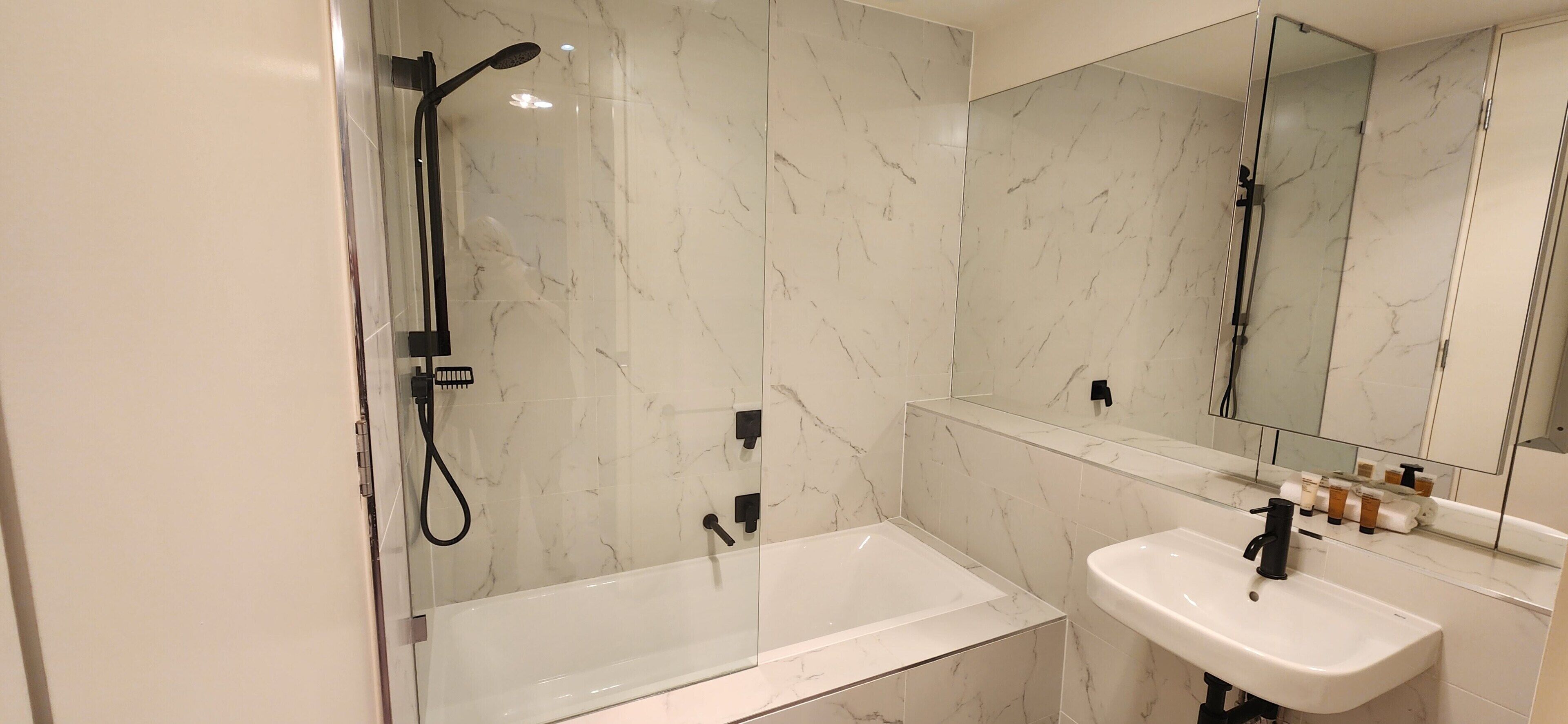 A modern bathroom with a glass-enclosed shower, a standalone bathtub, and a white sink with a mirror above.
