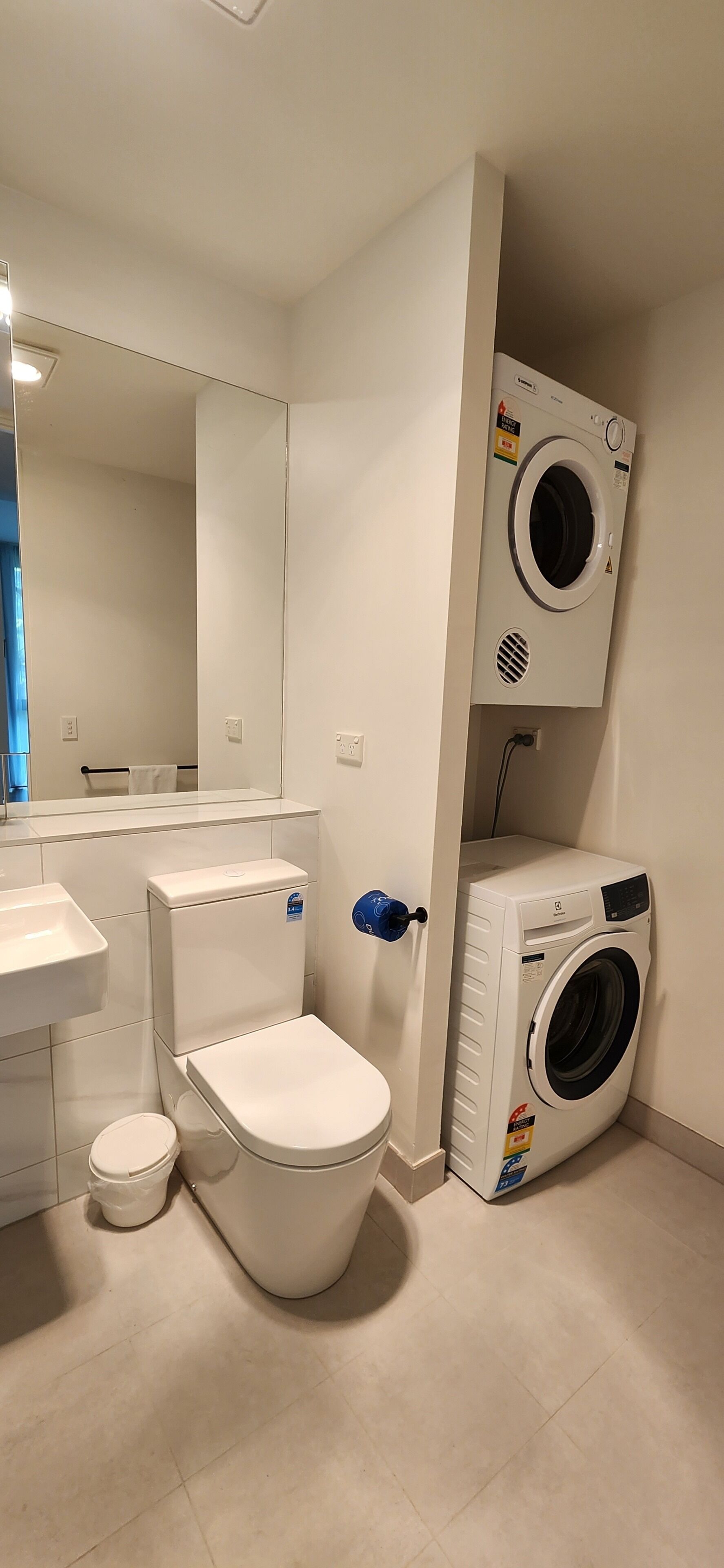 A compact bathroom with a toilet, sink, and a wall-mounted washing machine.
