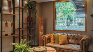 Ein gemütliches Wohnzimmer mit Ledersofa, Holzböden und einem großen Fenster mit Blick auf Bäume.