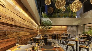 Ein Restaurant mit Holzwänden, runden Tischen und hängenden, kugelförmigen Leuchten.