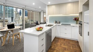 Una cocina moderna con armarios blancos, lavavajillas integrado y un amplio ventanal con vistas a la ciudad.