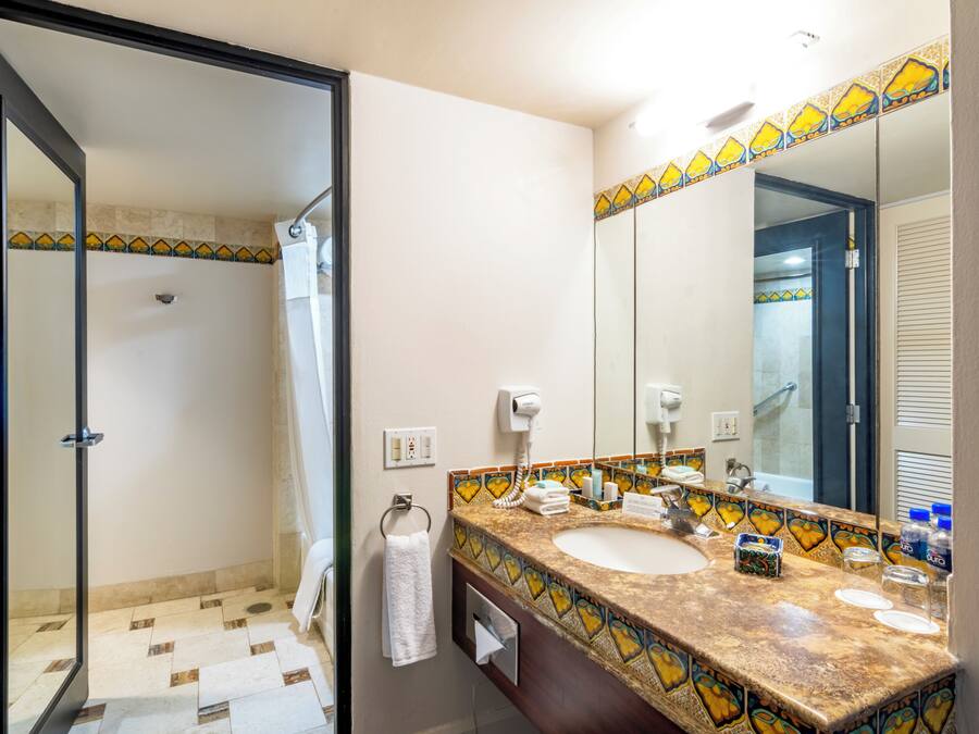 Een badkamer met een douche, een wastafel met spiegel en een handdoekhouder.