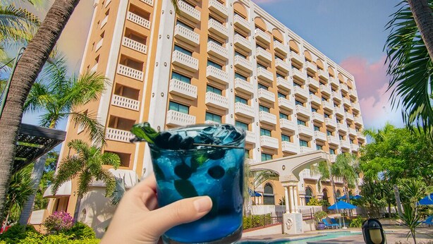 Ein Hotel mit mehreren Balkonen, einem Schwimmbad und Palmen.