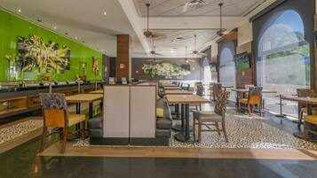 Un restaurante moderno con techos altos, paredes verdes y grandes ventanales.