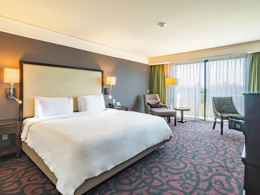 Een hotelkamer met een groot bed, een bureau, een stoel en uitzicht op de stad.