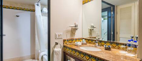 Un baño con ducha, lavamanos y espejo.