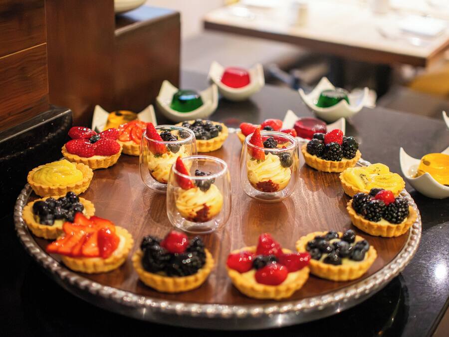 Una bandeja con diversos postres, incluyendo tartas y vasos con fruta.