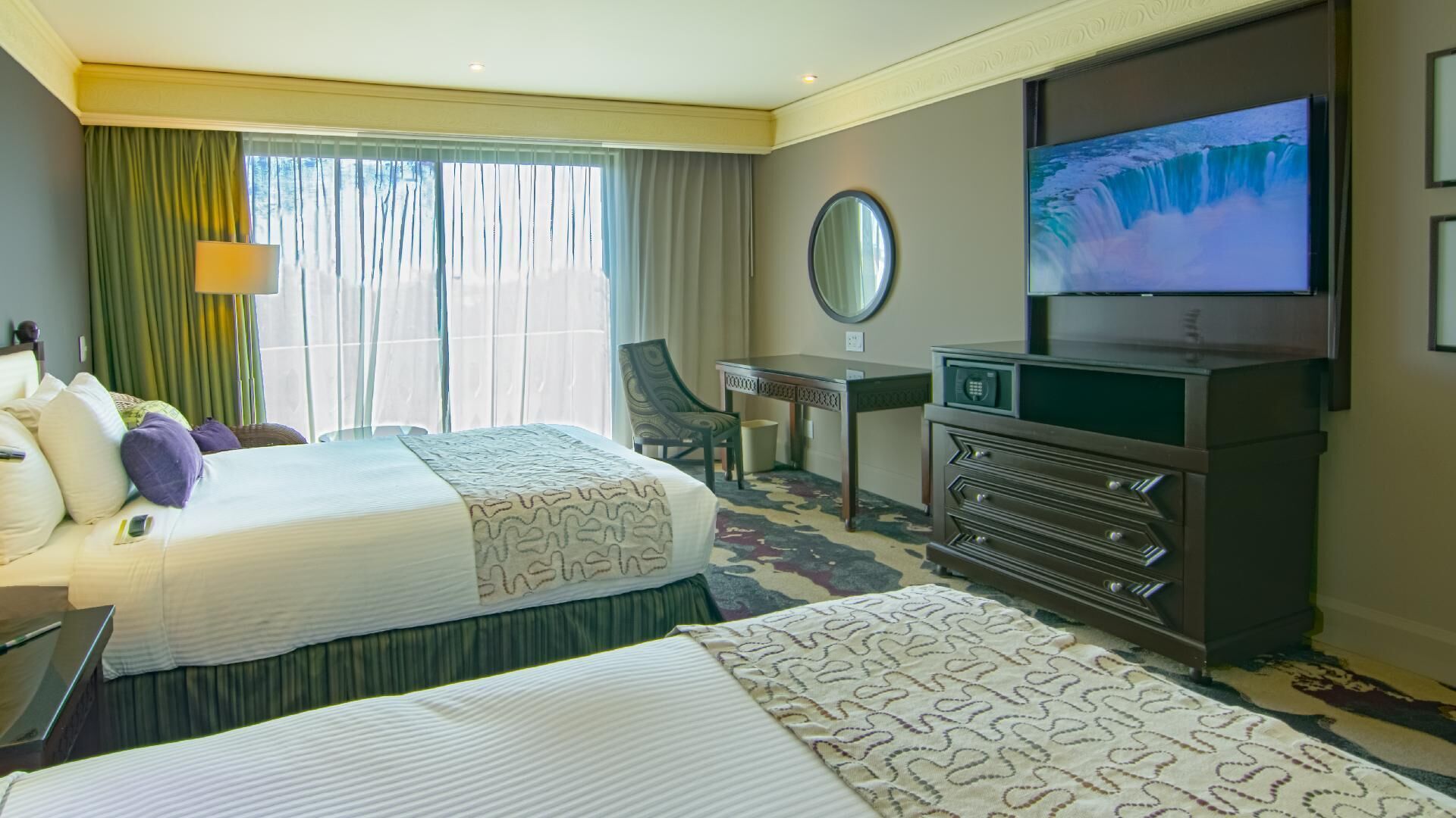 Una habitación de hotel con una cama, un escritorio, una silla, un televisor y un aparador.