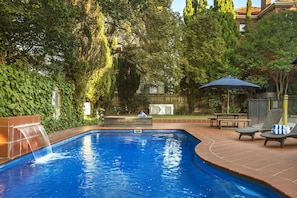 Una piscina al aire libre de temporada, sillones reclinables de piscina