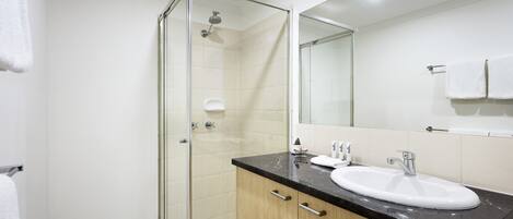 A modern bathroom with a glass-enclosed shower, a white sink, and wooden cabinets.