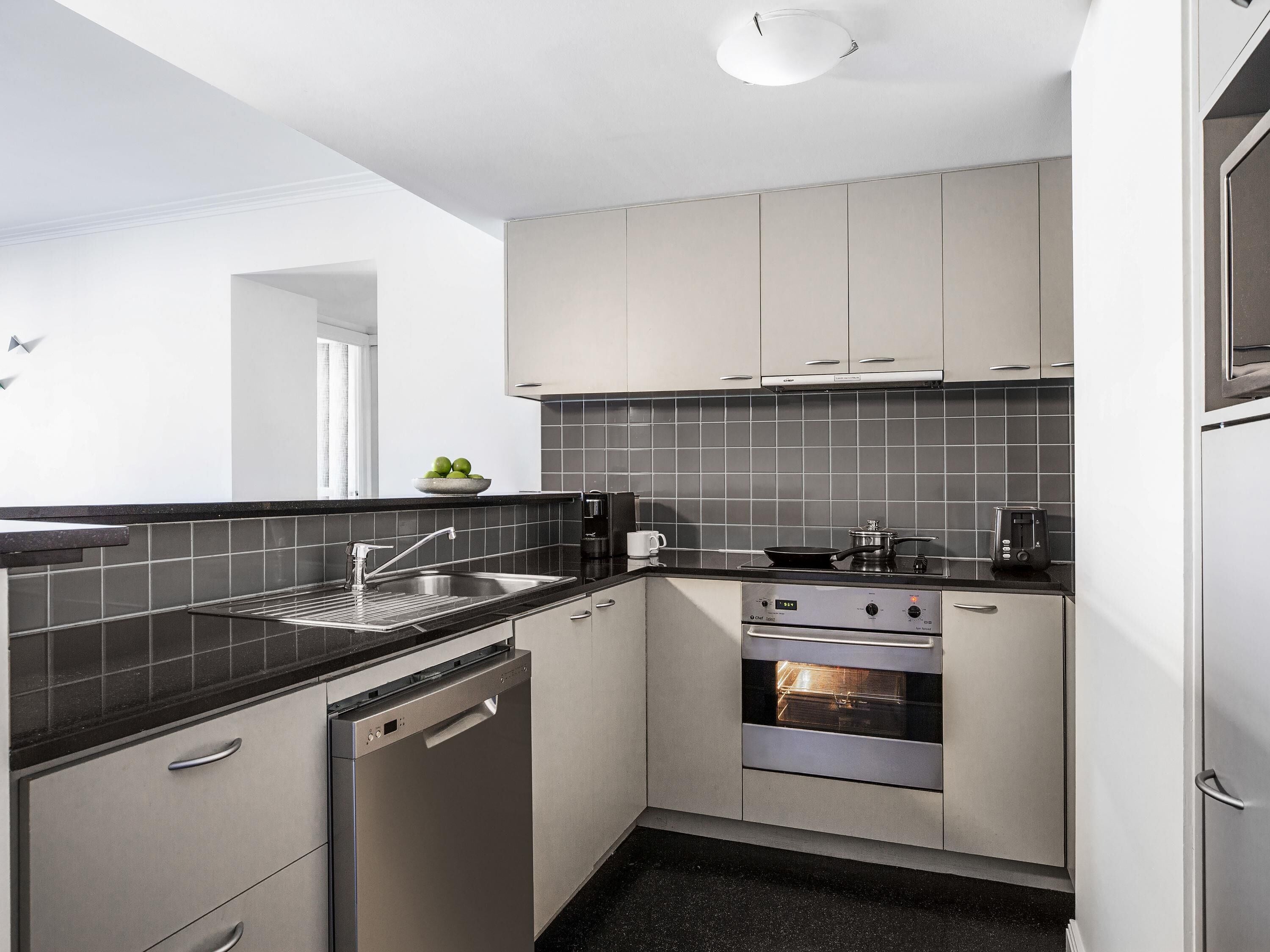 A modern kitchen with a dishwasher, oven, and a coffee maker.