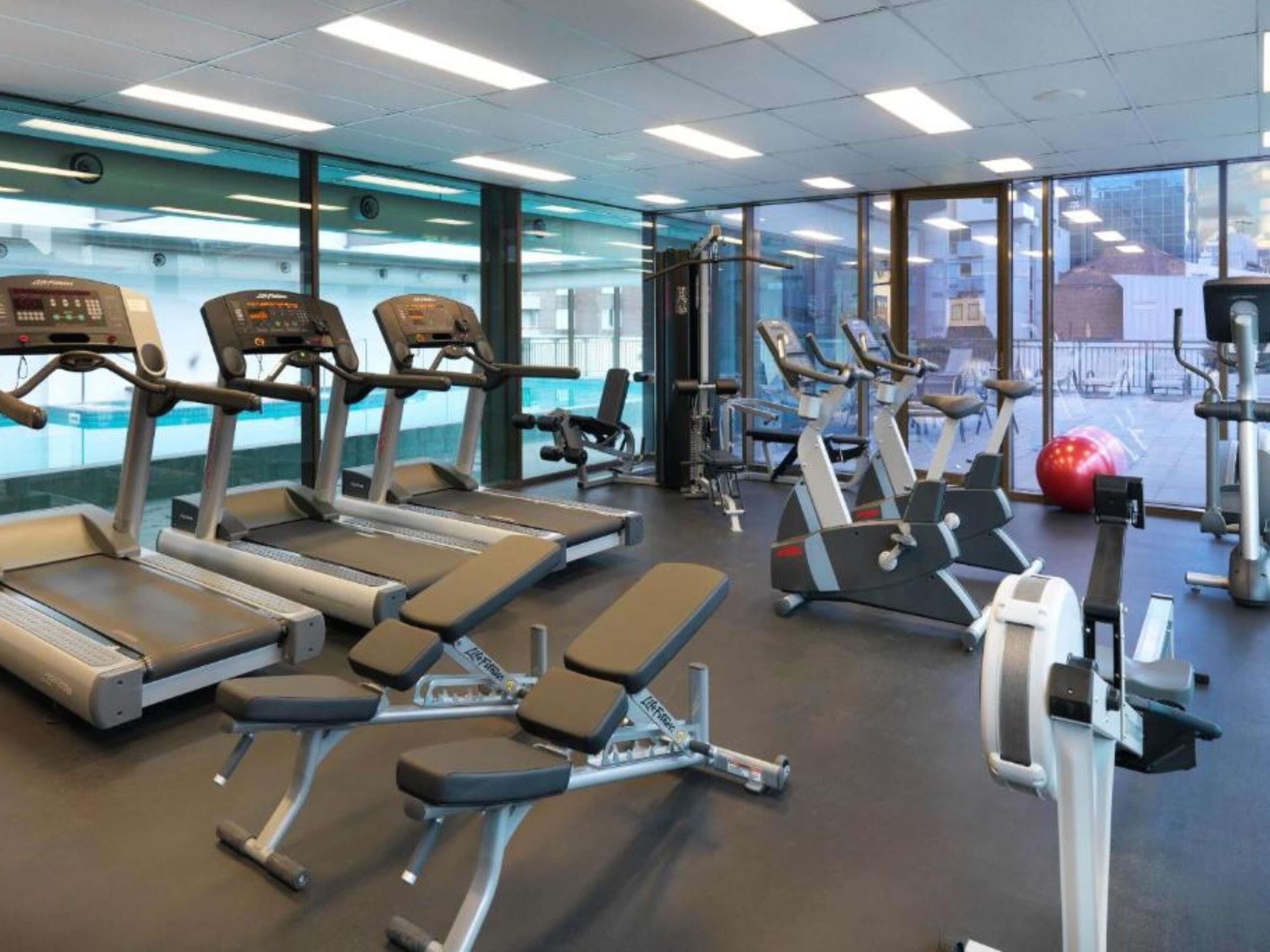 Une salle de sport équipée de tapis de course, de vélos elliptiques et de matériel de musculation.