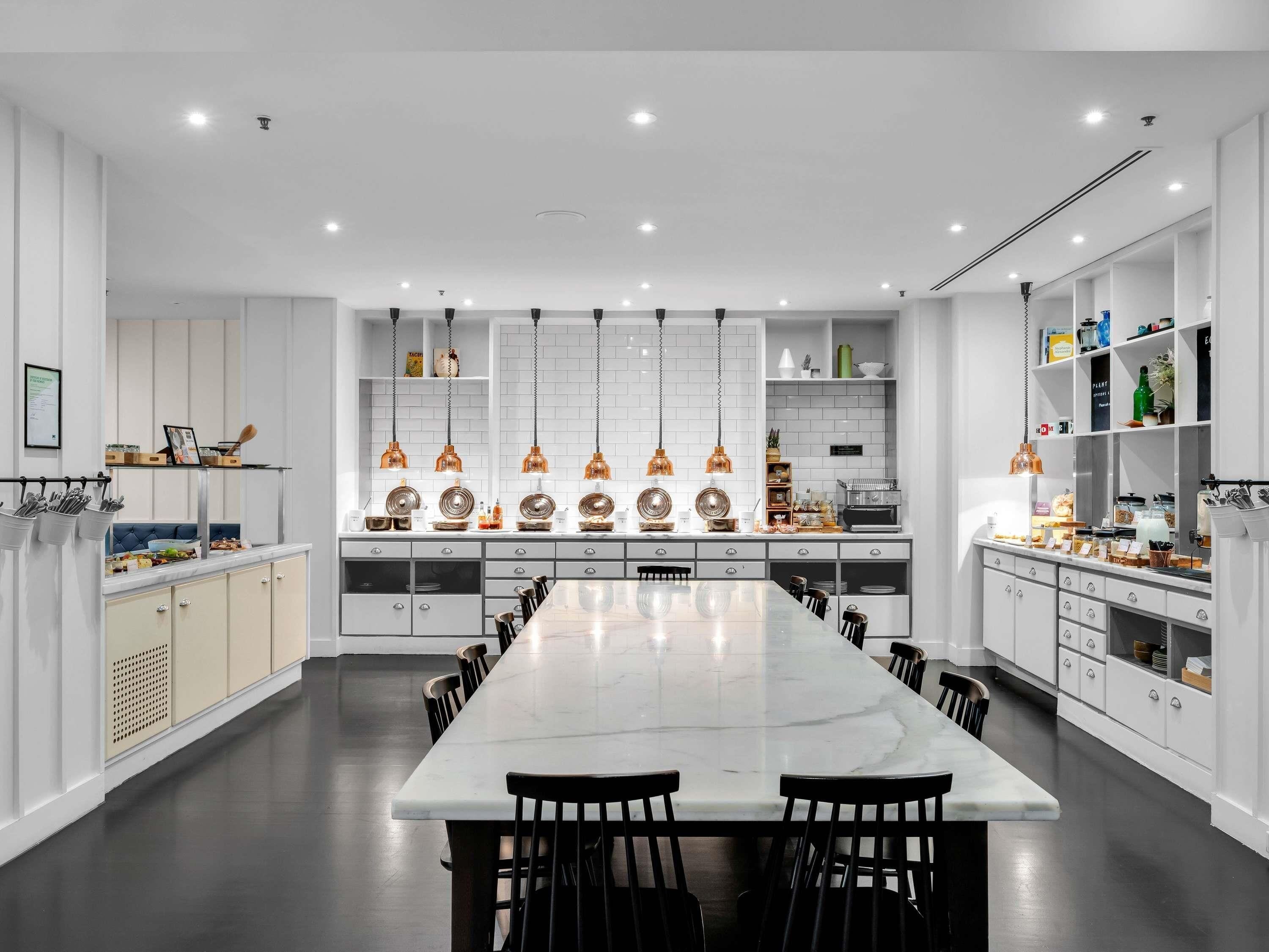 A modern kitchen with a marble island, pendant lights, and white cabinetry.