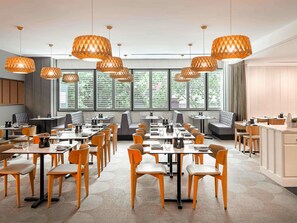 A modern dining area with multiple tables and chairs, large windows with greenery outside, and pendant lighting. - Mantra on Russell Melbourne (Melbourne)