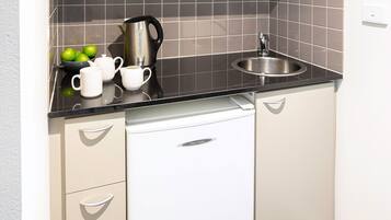 A kitchen with a black countertop, a stainless steel sink, and a white dishwasher.