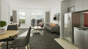 Eine moderne Wohnung mit Essbereich, einer Couch, einem Couchtisch und einer Küche mit Kühlschrank.