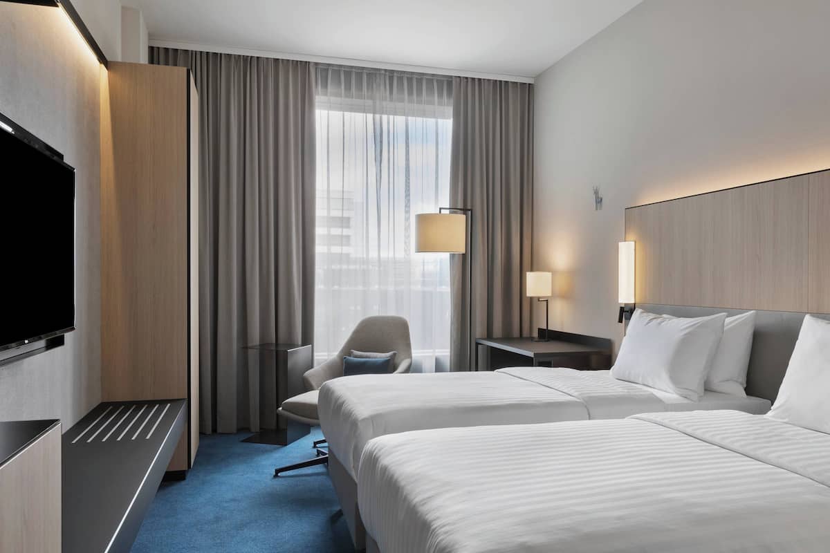 Une chambre d’hôtel avec deux lits, une télévision, un bureau et une chaise.