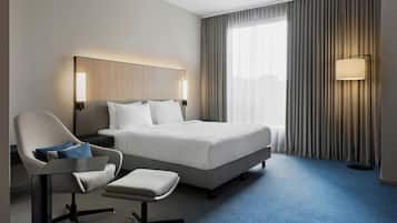 Ein Hotelzimmer mit Bett, Stuhl, Schreibtisch und Lampe.