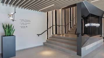 A modern staircase with a metal railing and a wall-mounted sign indicating the lobby and reception areas on the first floor.