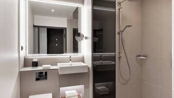Un baño moderno con un espejo grande, dos lavamanos, un inodoro y una zona de ducha.