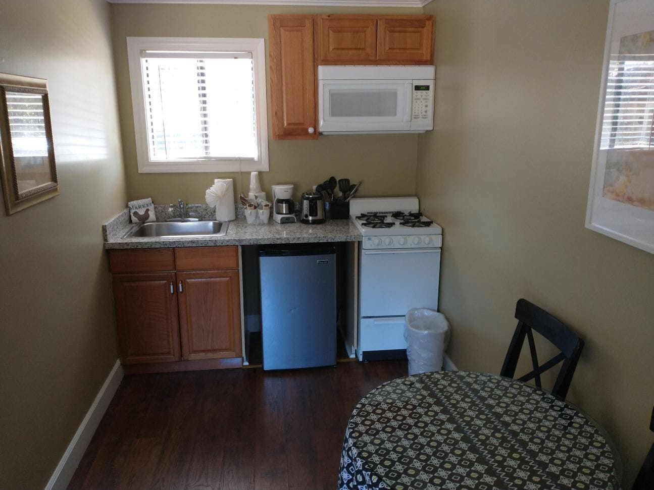 A compact kitchen with wooden cabinets, a built-in microwave, a refrigerator, and a sink.