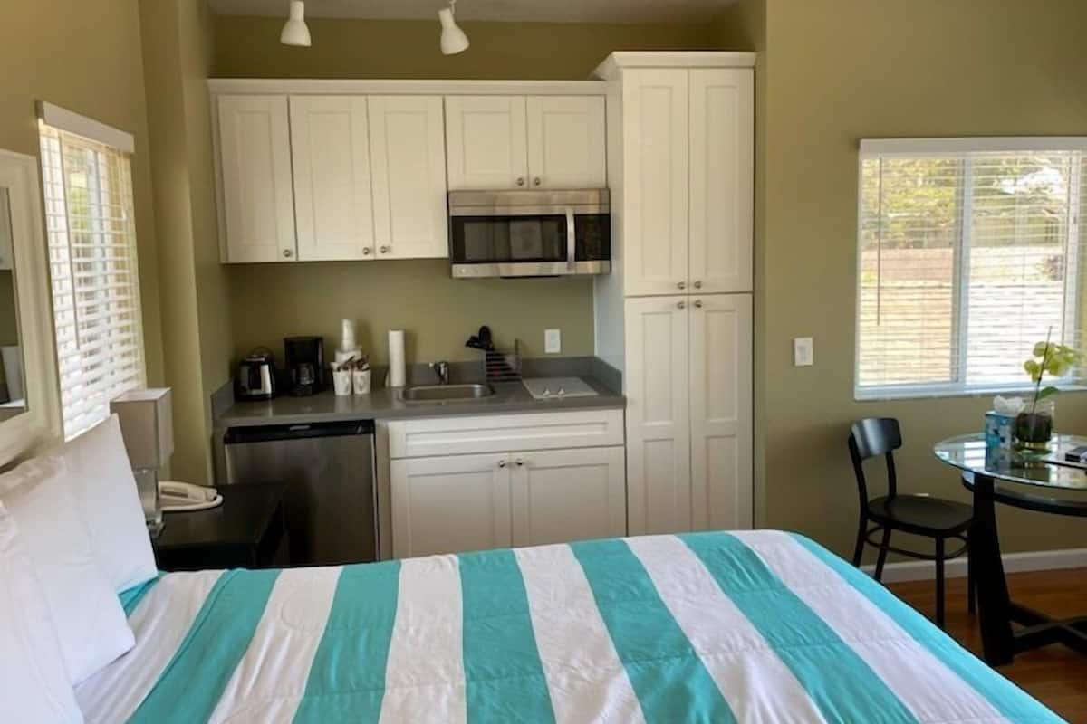 A compact room with a bed, kitchenette, and a small dining area.