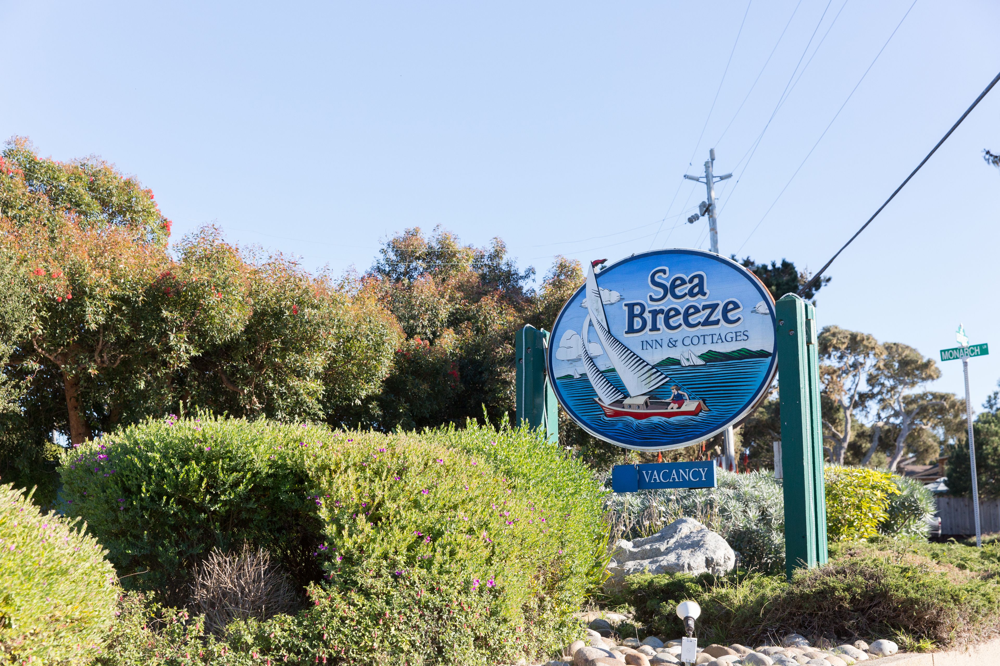 A sign for Sea Breeze Inn & Cottages with a view of the surrounding greenery and a clear sky.