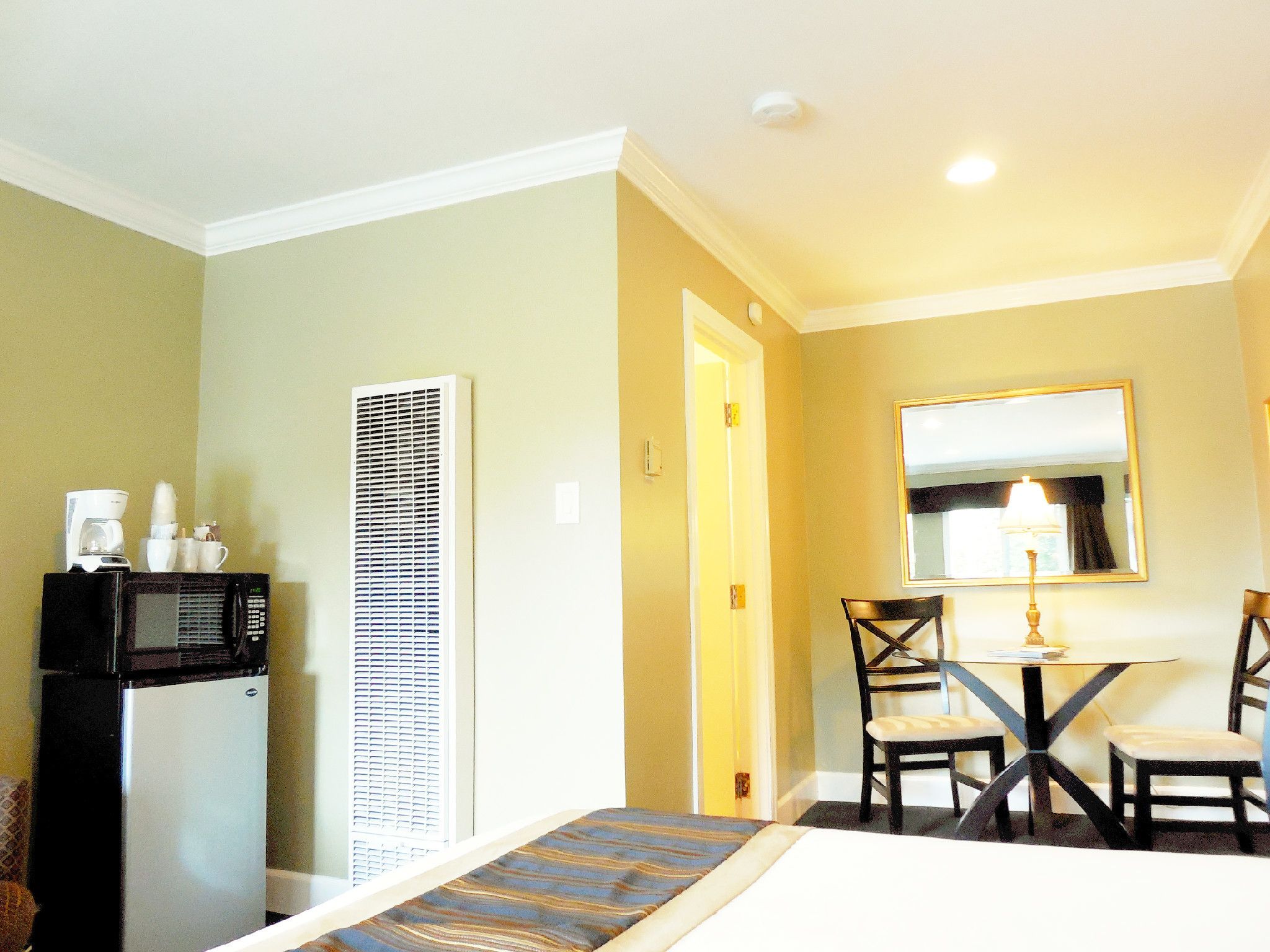 A hotel room with a bed, a desk with a chair, a microwave, and a coffee maker.
