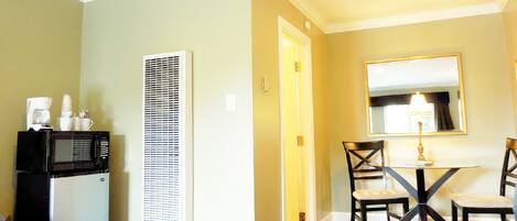 A hotel room with a bed, a desk with a chair, a microwave, and a coffee maker.