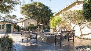 An outdoor patio area with stone flooring, benches, and a fire pit.