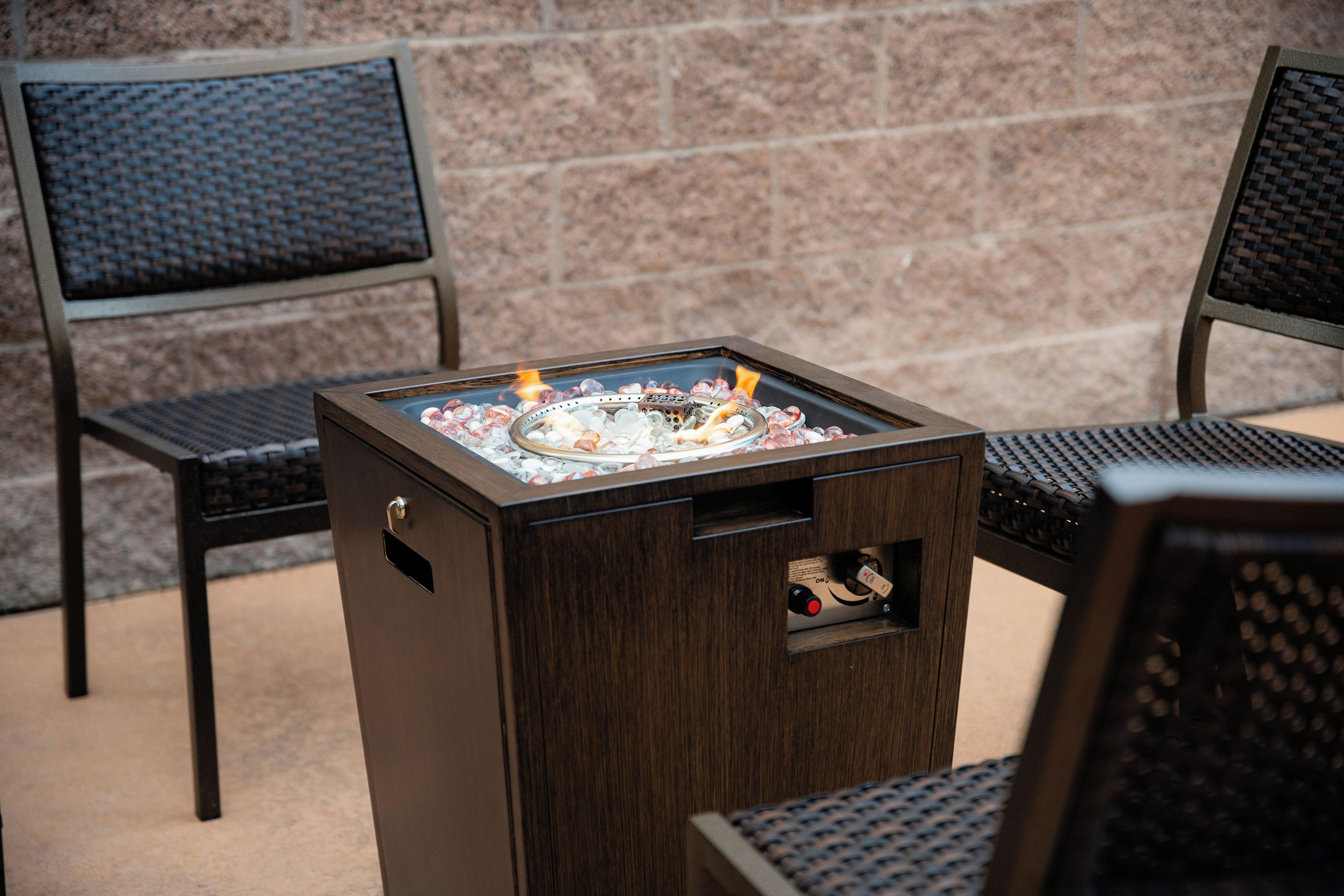 A portable outdoor grill with a metal grate and a control panel, placed on a wooden stand.