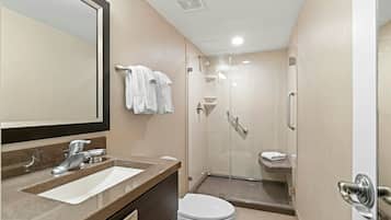 A modern bathroom with a sink, mirror, toilet, and glass-enclosed shower.